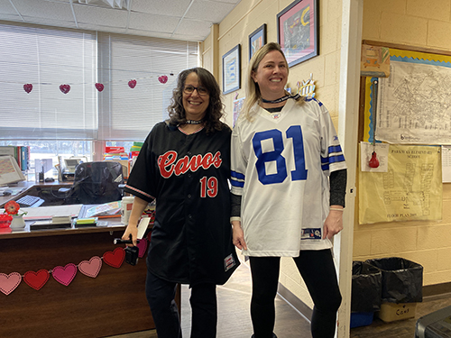 Two woman wearing numbered football jerseys